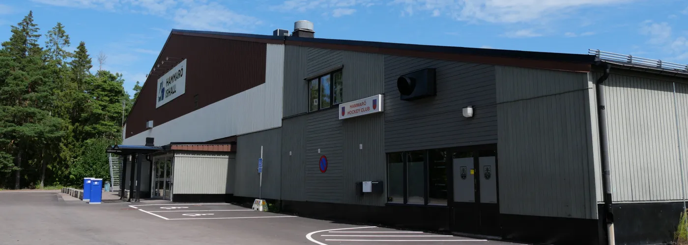 Sidan av Hammarö ishall i Skoghall med sin mörka överdel och parkeringen framför – Hammarö ishall