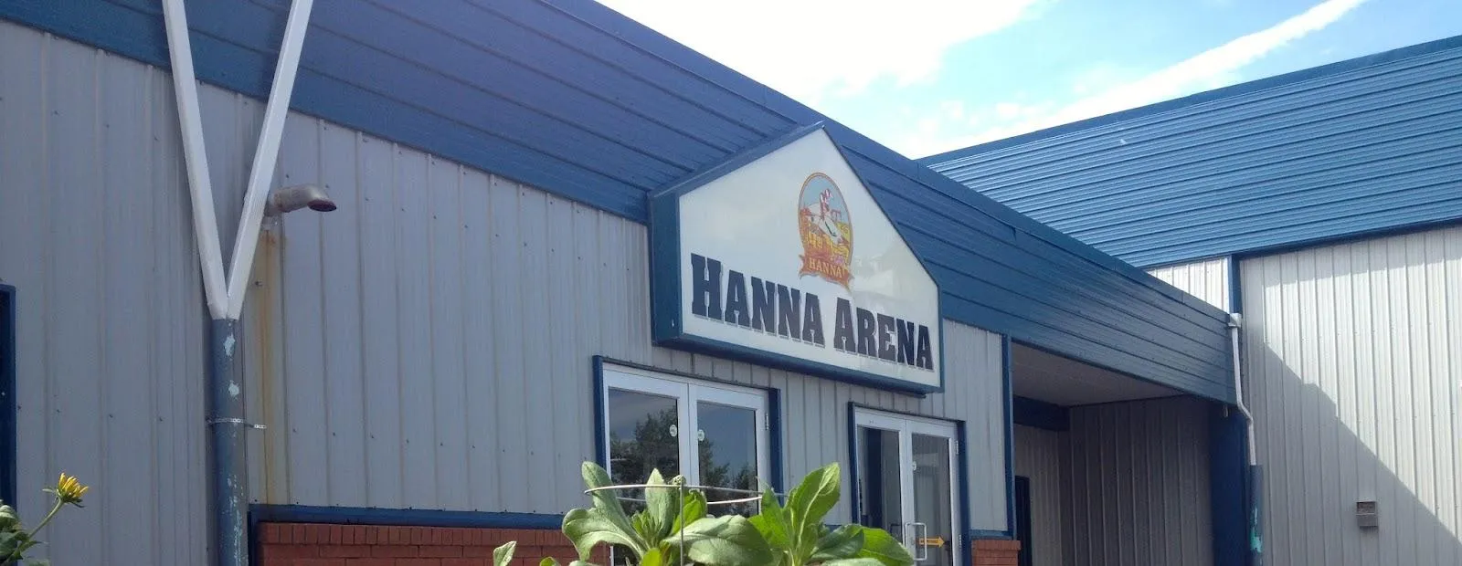 The Hanna Arena entrance, a blue-trimmed gable signed Hanna Arena between grey metal-clad walls. — Hanna Arena