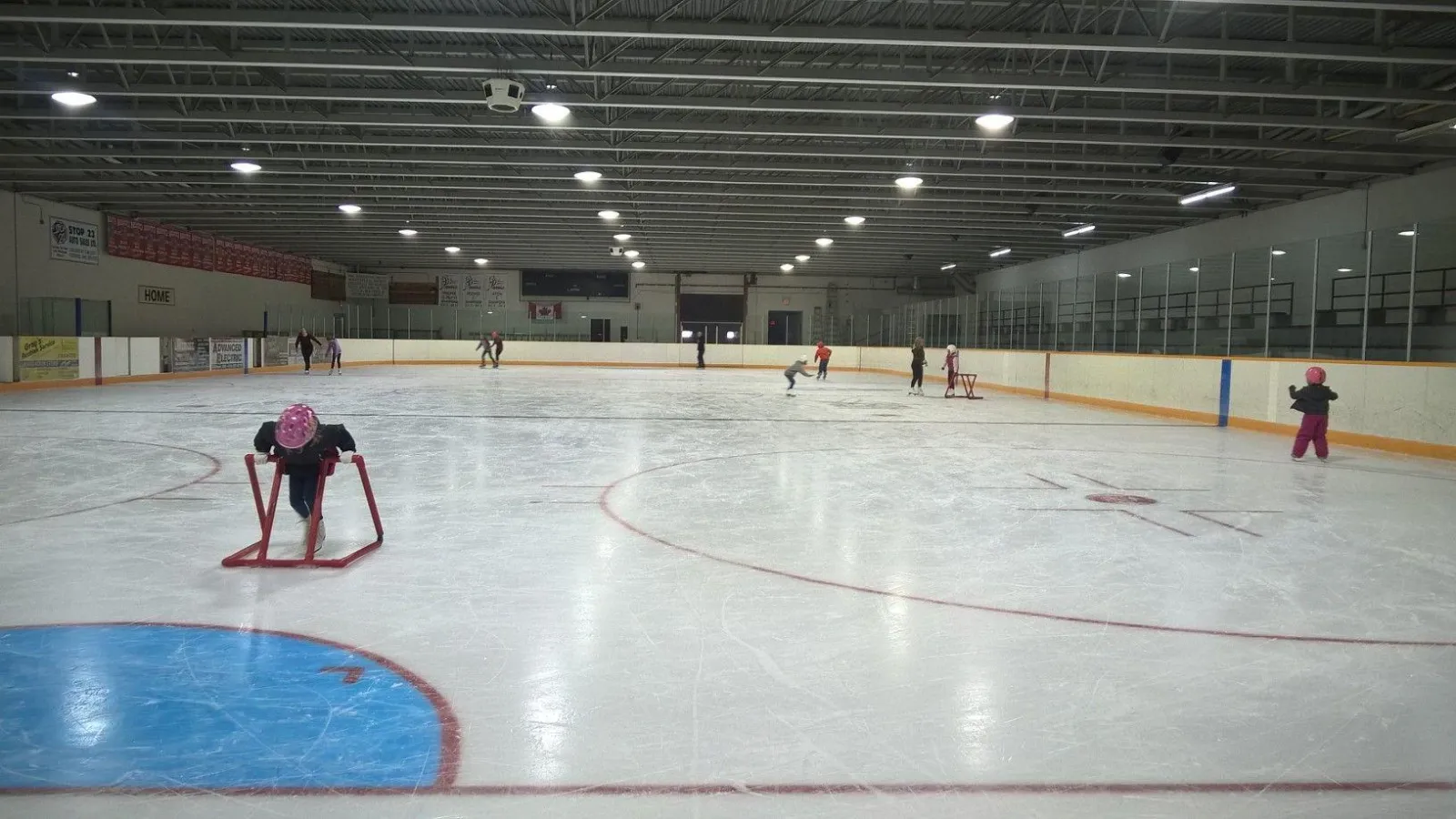 Skaters and a child with a training walker on the ice at a public skate in the Harriston Arena — Harriston Arena