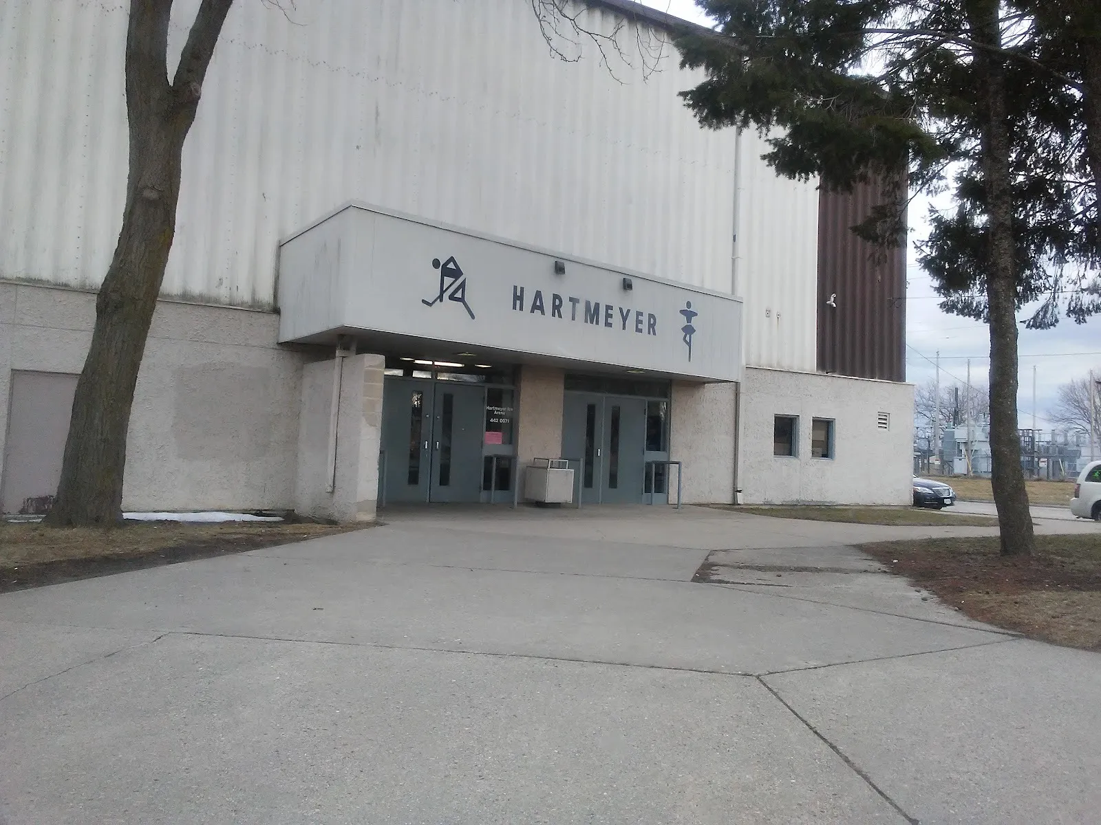 The Hartmeyer entrance, its name between skater figures on a canopy over two sets of doors in the tall ribbed wall — Hartmeyer Ice Arena
