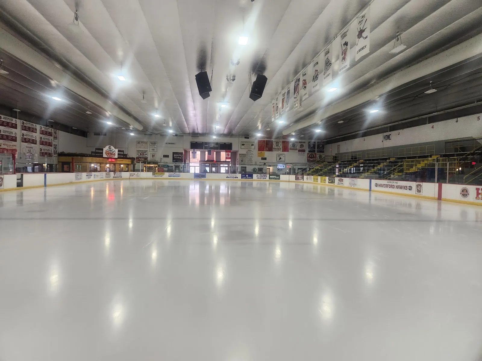 The empty Skatium sheet at ice level, with the Haverford Hawks boards, the stands on the right and team banners along the roof — Haverford Township Skatium