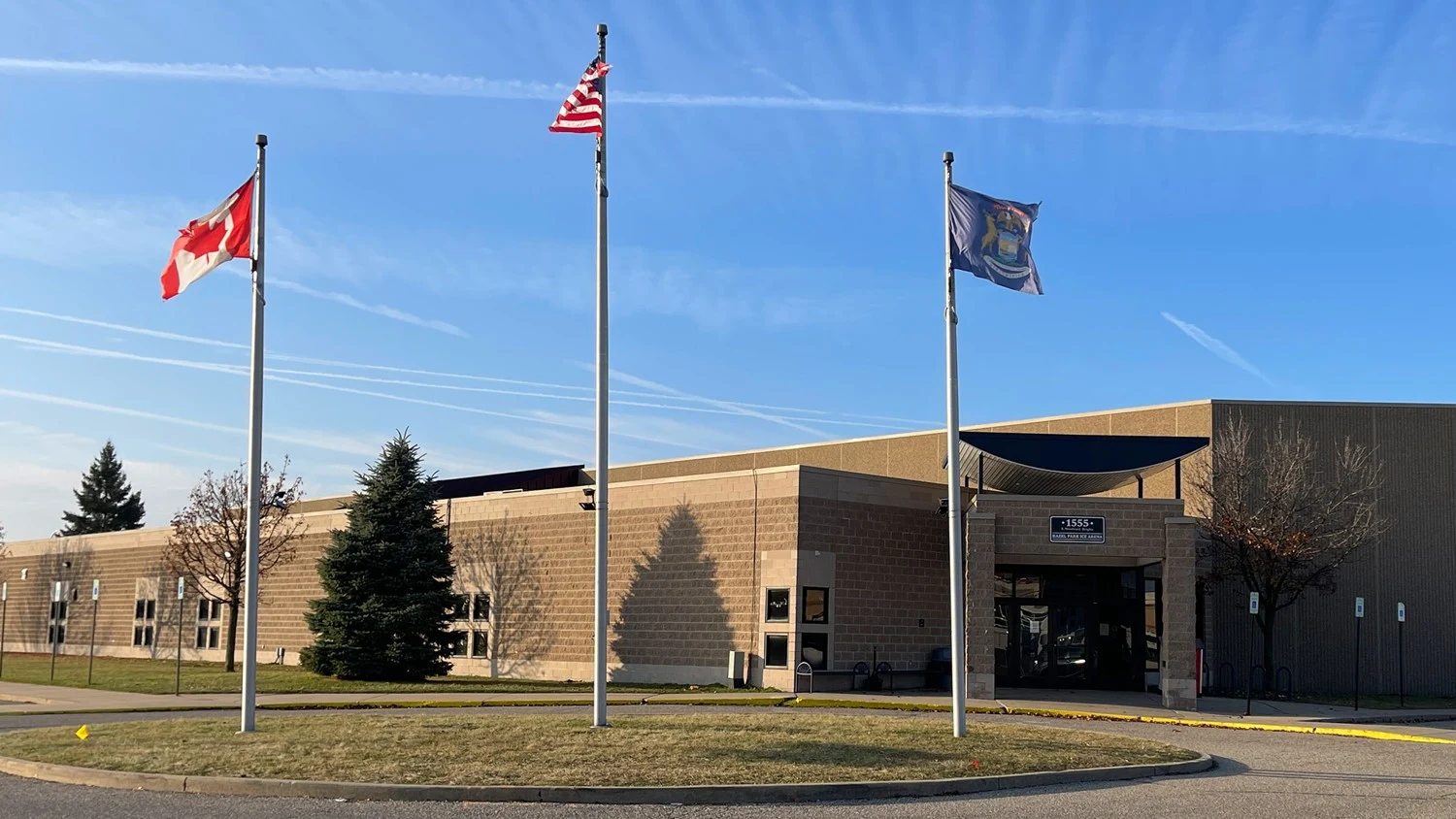 El edificio de ladrillo de la arena de Hazel Park, la marquesina de la entrada y tres astas de bandera. — Hazel Park Ice Arena