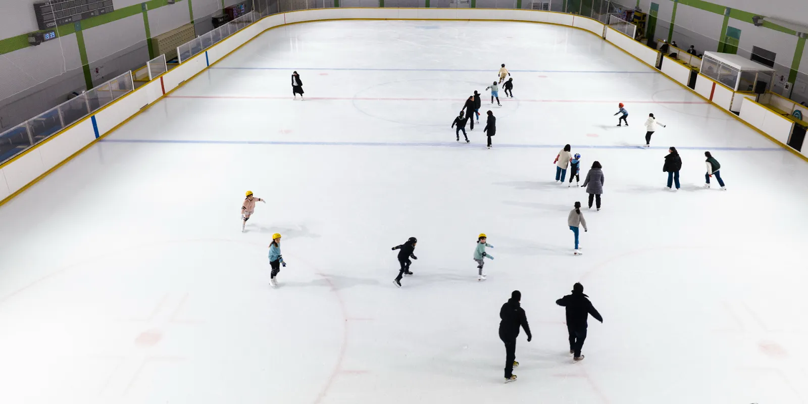 The ice sheet of the Higashiyamato Skate Center seen from above the boards, with skaters spread out over the surface — Higashiyamato Skate Center