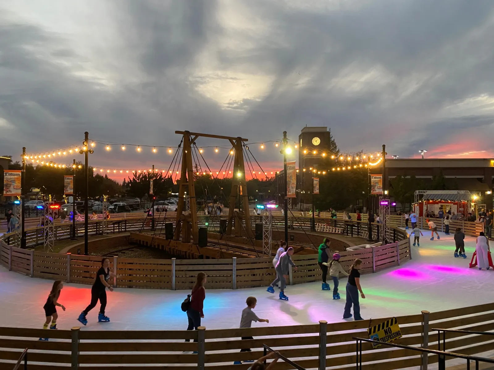 Skaters on the lit Folsom Historic District ice rink at dusk — Historic Folsom Ice Rink