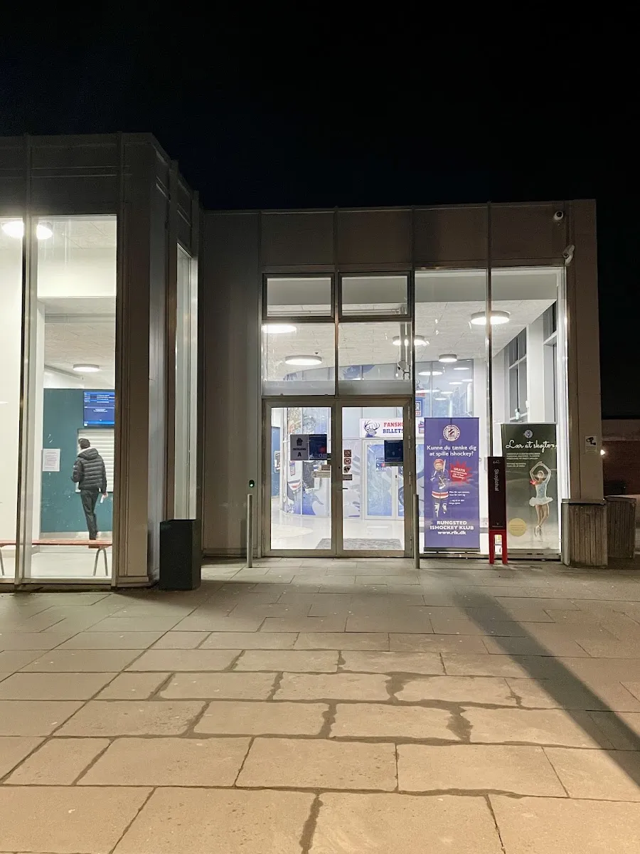 The glass entrance of Hørsholm Skøjtehal at night, with the Skøjtehal sign and club posters beside the doors. — Hørsholm Skøjtehal