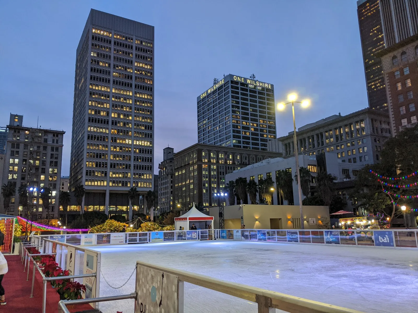 The Holiday Ice Rink in Pershing Square with the downtown Los Angeles skyline behind it (Google Maps listing photo) — Holiday Ice Rink Pershing Square