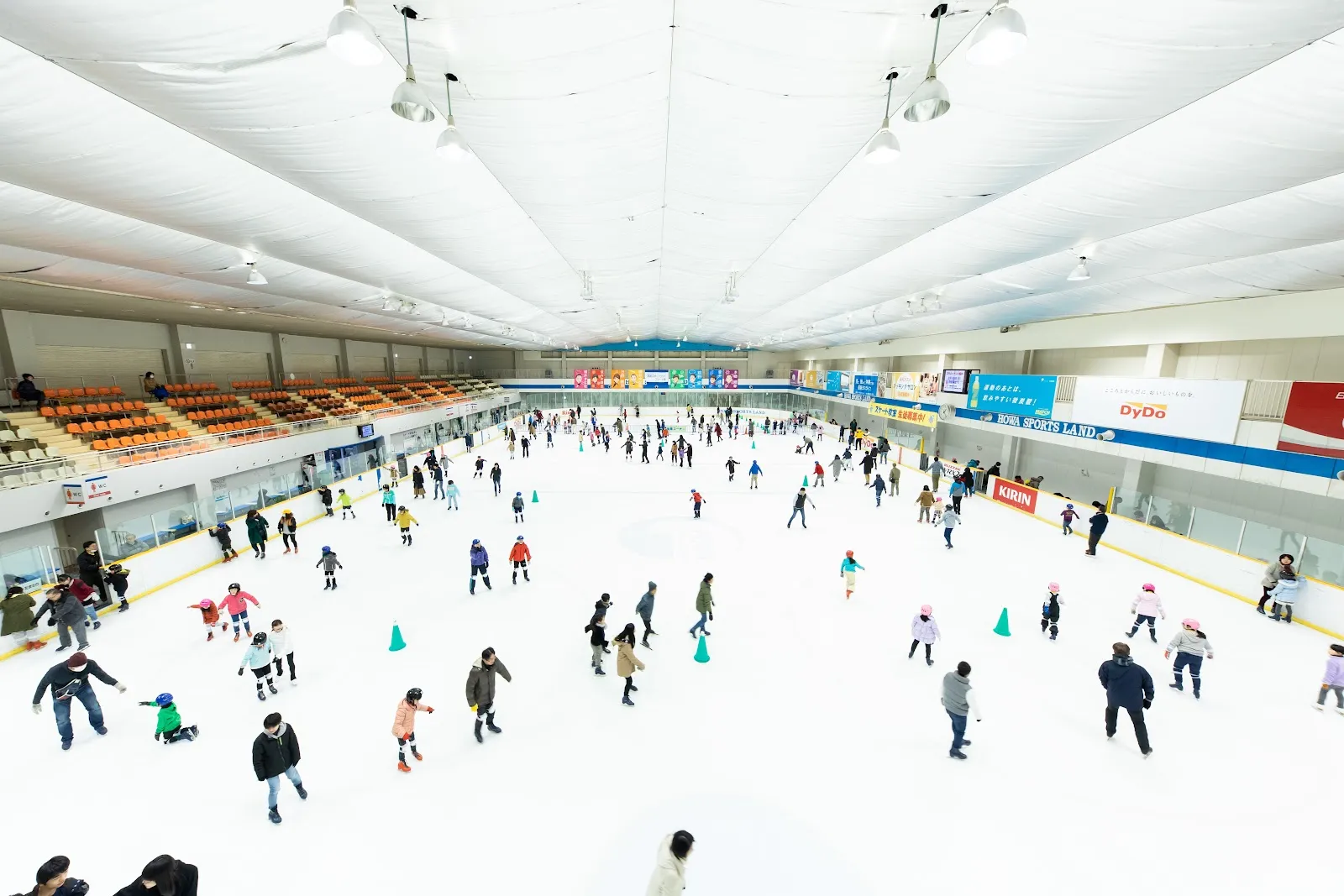A wide view of the Howa Minato rink during a public session with many skaters spread over the ice — Howa Minato Sports & Culture Skate Rink