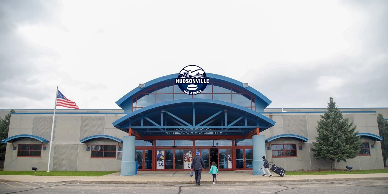 Hudsonville Ice Arena's entrance beneath its blue arched canopy and arena sign. — Hudsonville Ice Arena