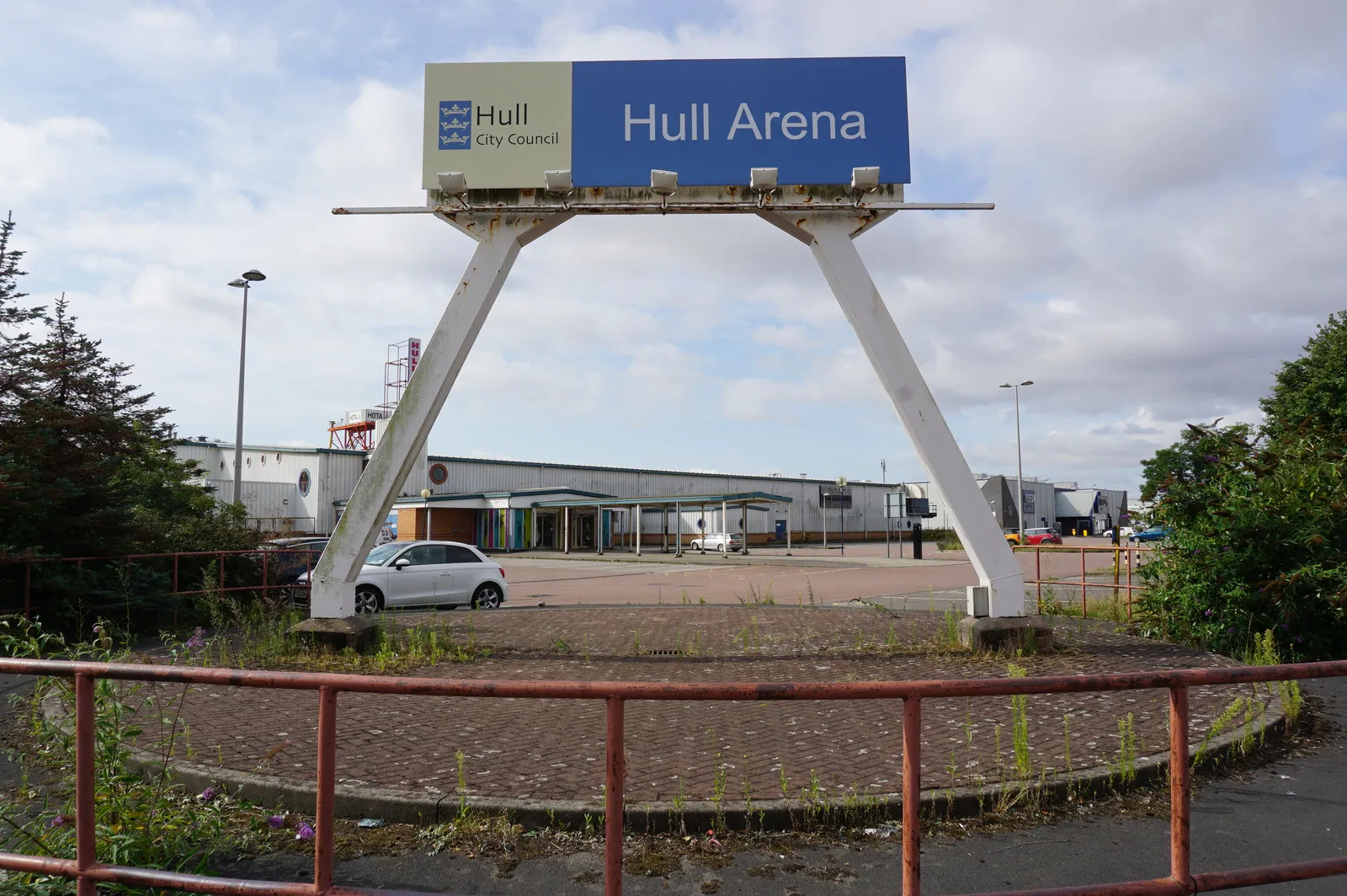 The Hull Arena sign on its tall white frame at the car park entrance, with the low grey arena building behind it. — Hull Ice Arena
