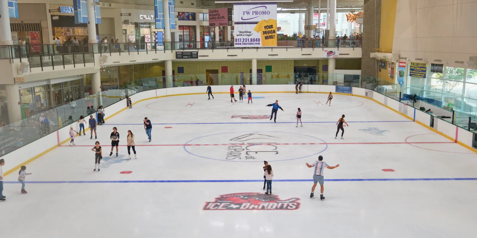 Patinadores en la pista de tamaño completo de ICE at The Parks, vista desde el nivel superior del centro comercial. — ICE at The Parks