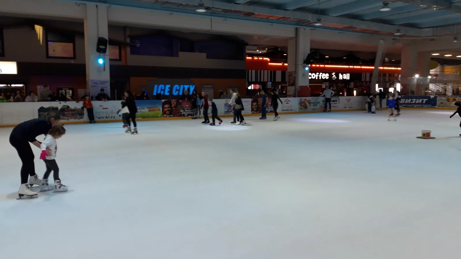 The ICE CITY rink inside the Aurora Mall in Samara, skaters at a distance and the mall shops beyond the boards — Ice City Avrora Mall Samara