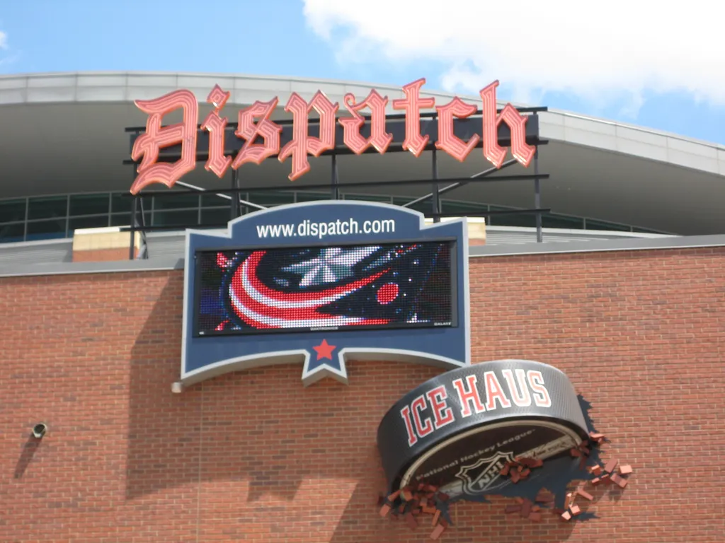 A puck-shaped sign bursting through the brick wall — OhioHealth Ice Haus