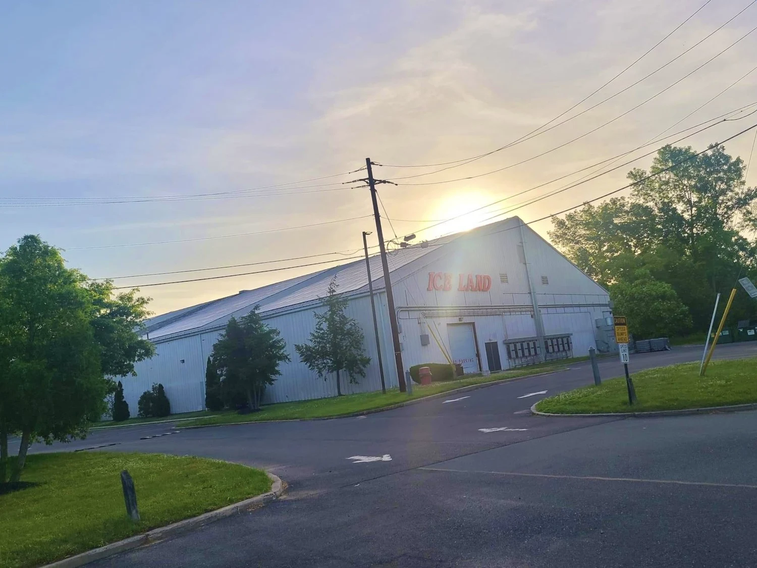 The Ice Land building and entrance drive in late-day sunlight. — Ice Land Skating Center