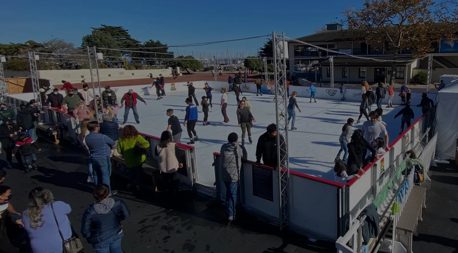 Patinadores en la pista exterior de Custom House Plaza, vistos desde las vallas. — Ice Skating by the Bay