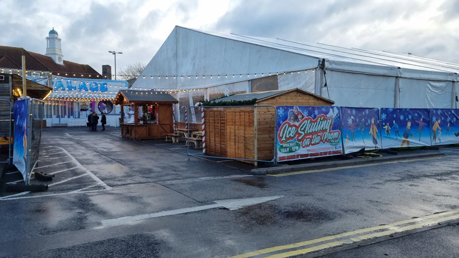 The white marquee and wooden chalets of the Bognor Regis ice rink on the London Road car park in daylight — Ice Skating in the Park (Bognor Regis)