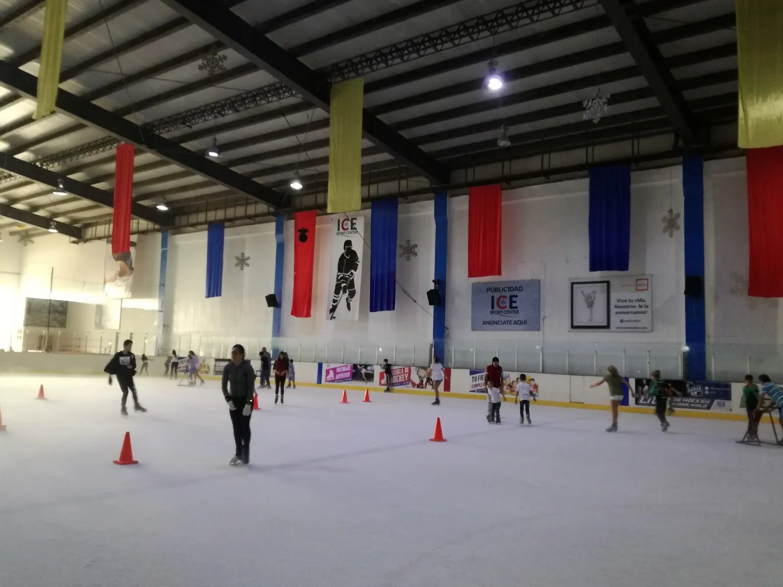 The Ice Sport Center sheet during a public session, under coloured banners and an ICE Sport Center hockey banner — Ice Sport Center