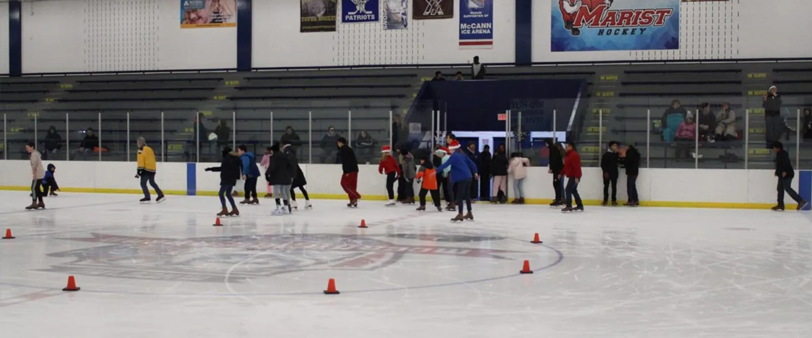 Public skaters on the McCann Ice Arena rink at Ice Time Sports Complex, with a "McCann Ice Arena" banner over the bleachers and boards. — Ice Time Sports Complex