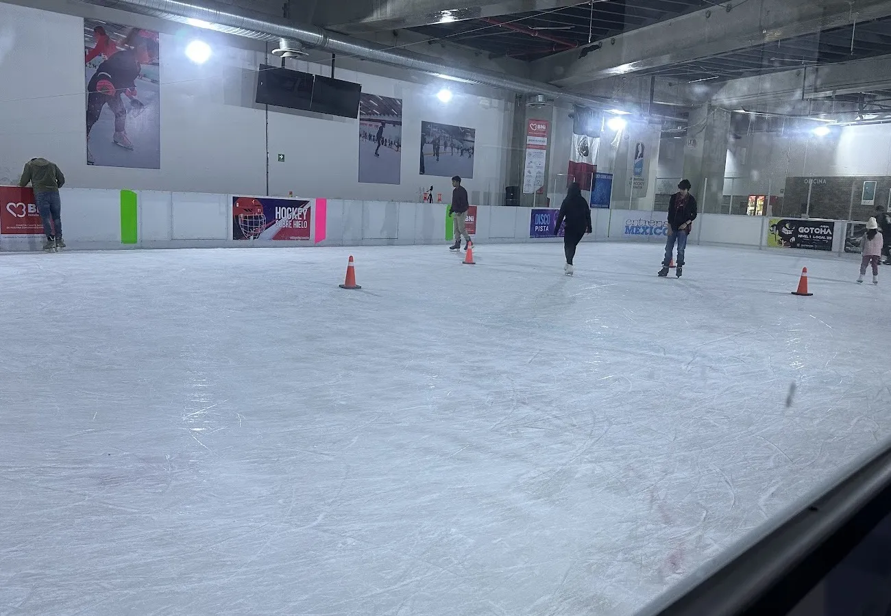 The Ice Town rink at Sentura seen through the rinkside glass, with figure skating and hockey banners on the boards — Ice Town Sentura