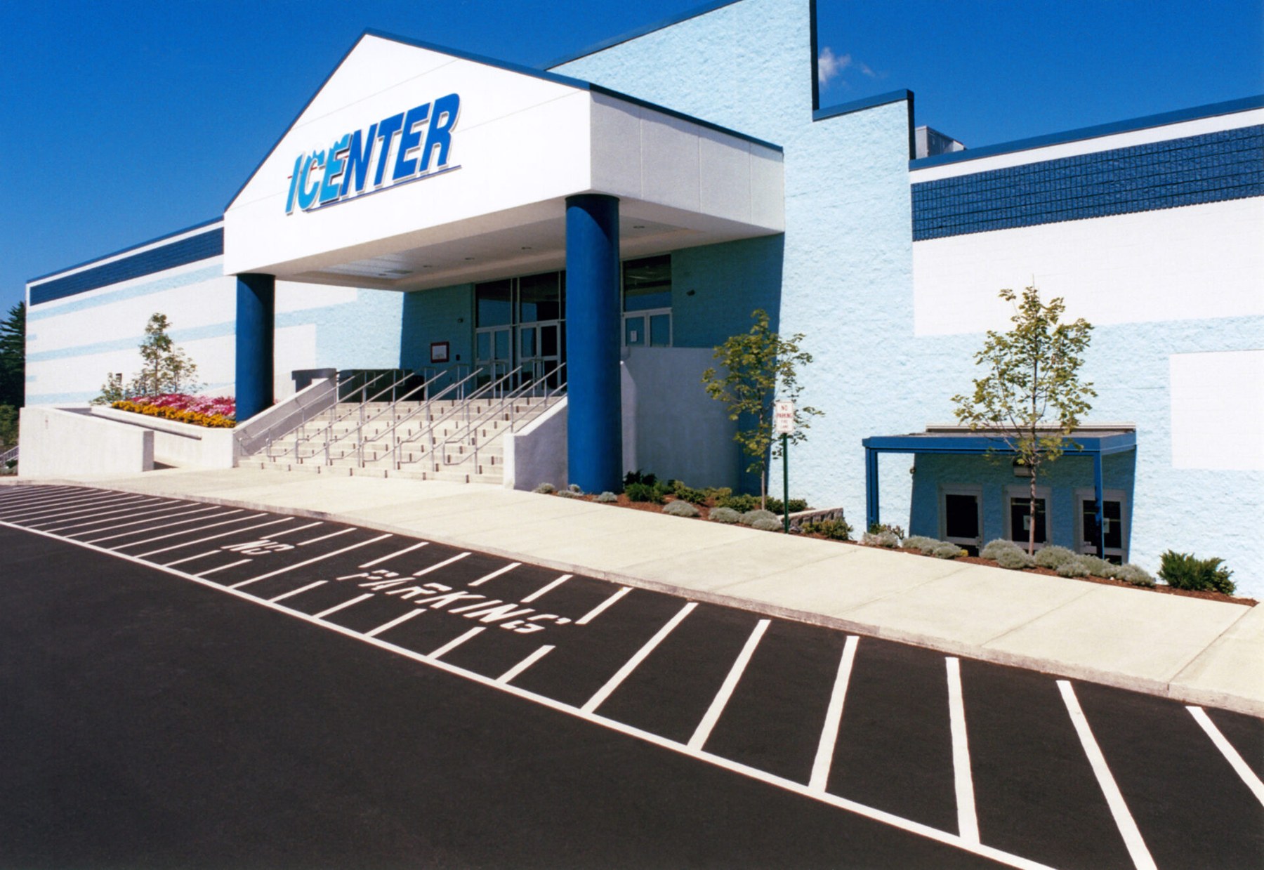 The iCenter’s blue-and-white entrance, with steps up to the doors beneath a gabled canopy. — The Icenter