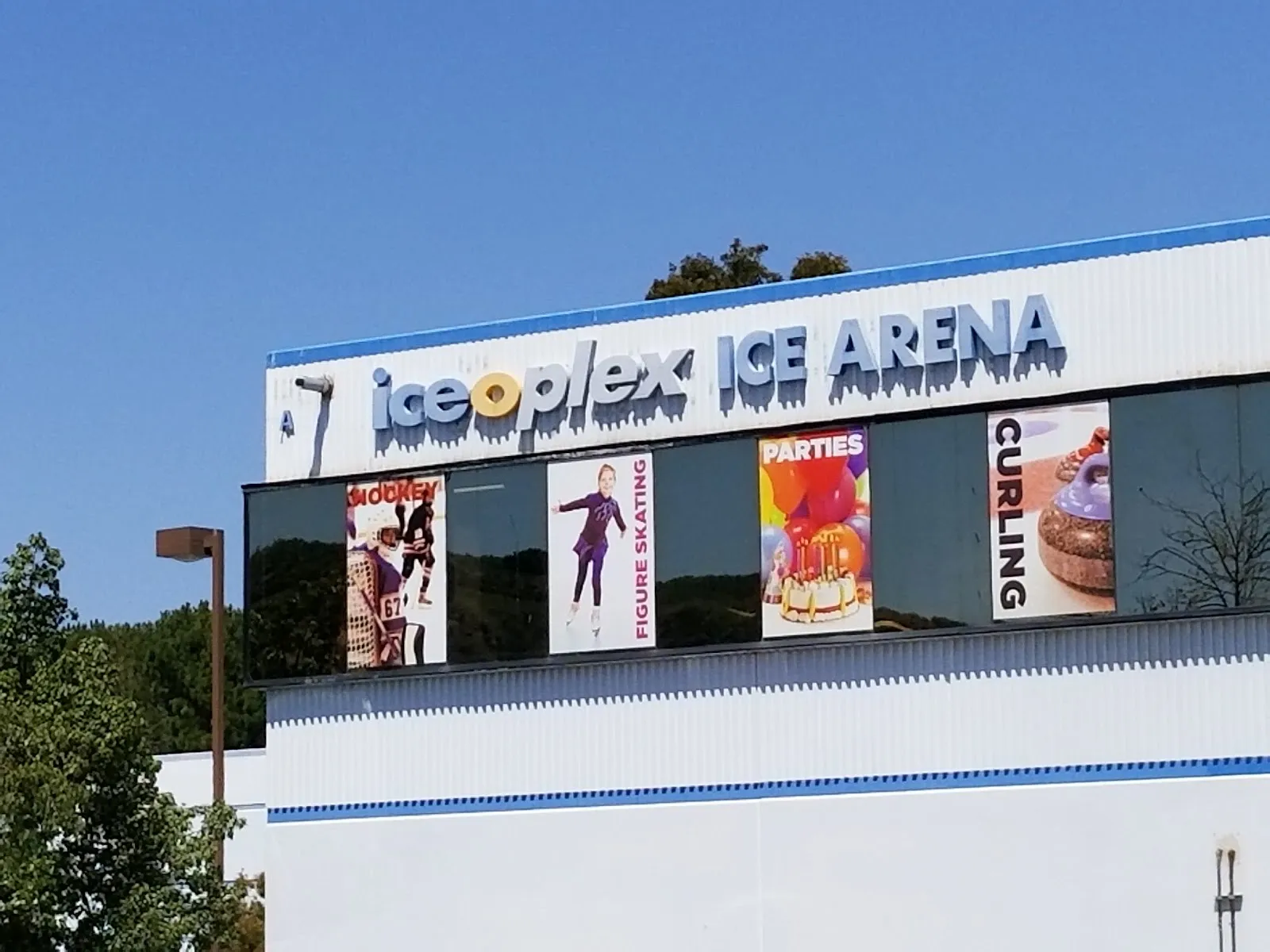 El edificio de Iceoplex Ice Arena en Simi Valley, con su nombre en letras azules sobre una franja de ventanas con mantas de programas — Iceoplex