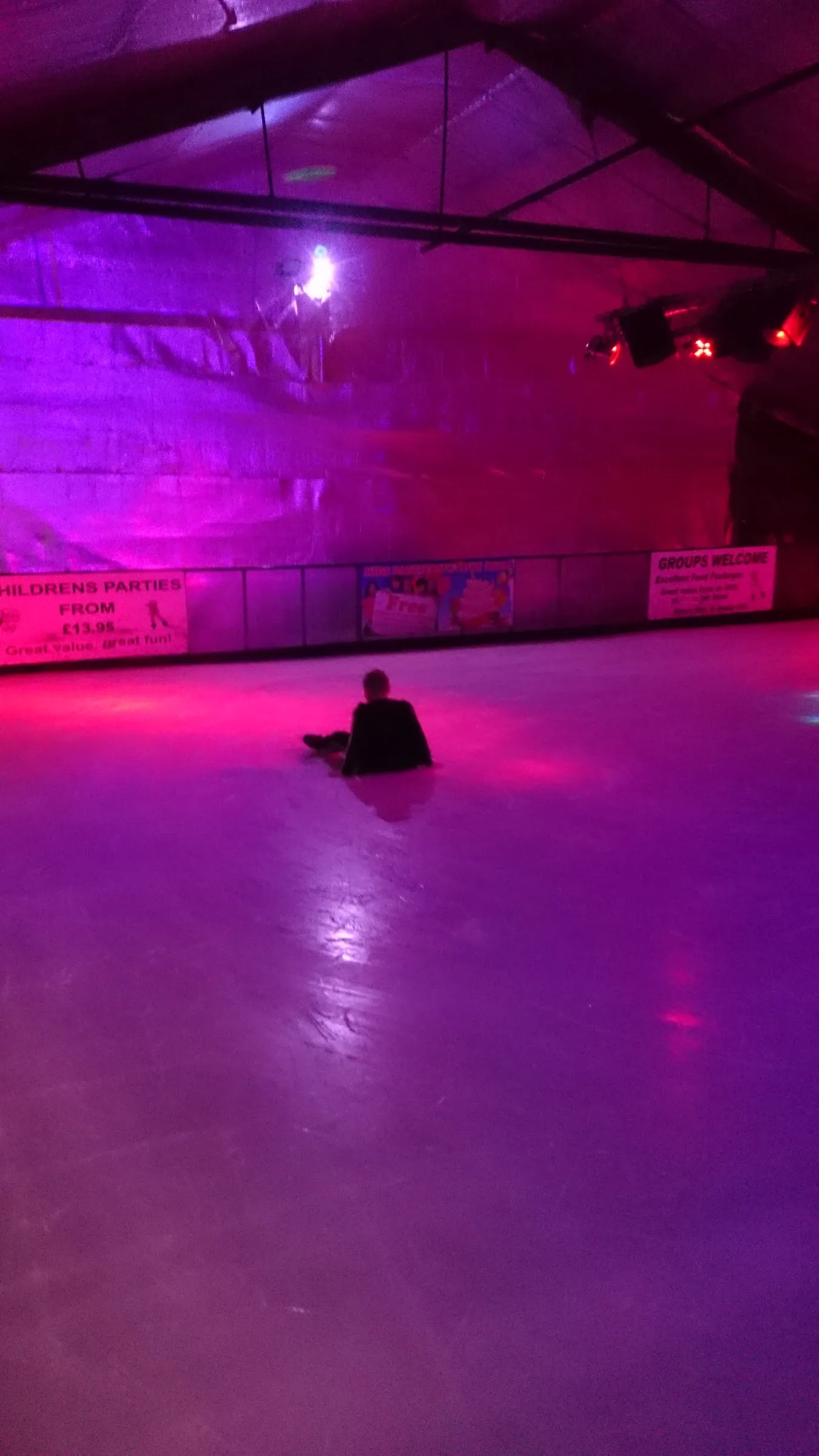 The indoor real-ice rink at IceQuest under coloured session lighting. — IceQuest Malvern