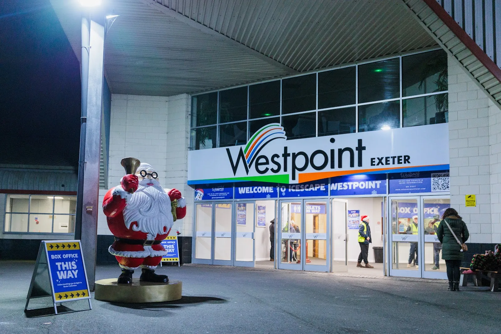 The entrance of Westpoint Arena in Exeter at night, with the Icescape welcome sign and a Santa figure by the box-office board — Icescape Westpoint