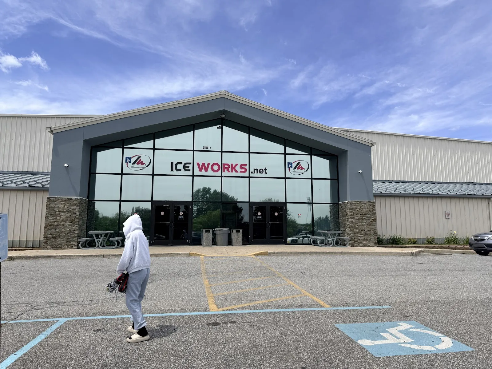 The IceWorks entrance, a gabled glass front with the IceWorks name set between the long metal rink buildings, across the parking lot. — IceWorks Skating Complex