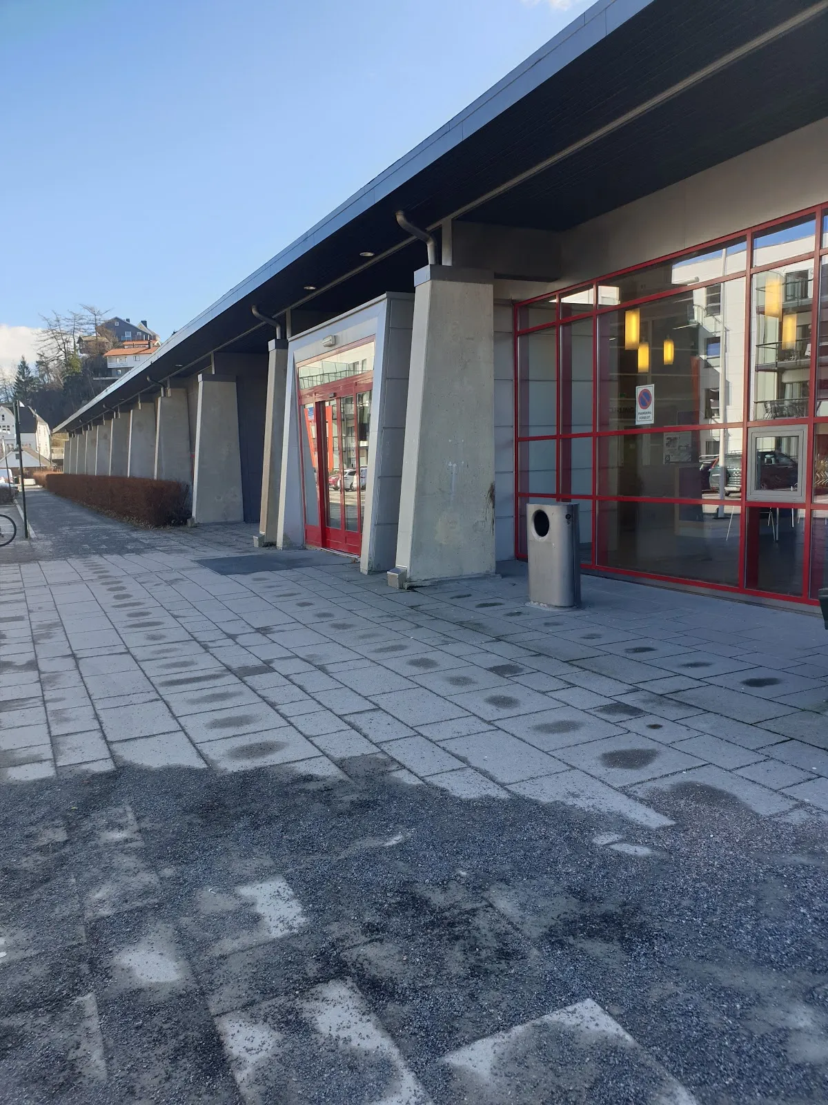 The side of Idda Arena with its covered walkway, glazed entrance and red window frames. — Idda Arena (ishall)