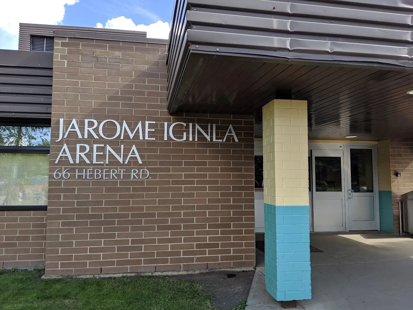 La entrada de ladrillo de Jarome Iginla Arena en St. Albert, con el nombre de la arena y la dirección 66 Hebert Rd en el muro junto a las puertas — Jarome Iginla and Kinex Arenas