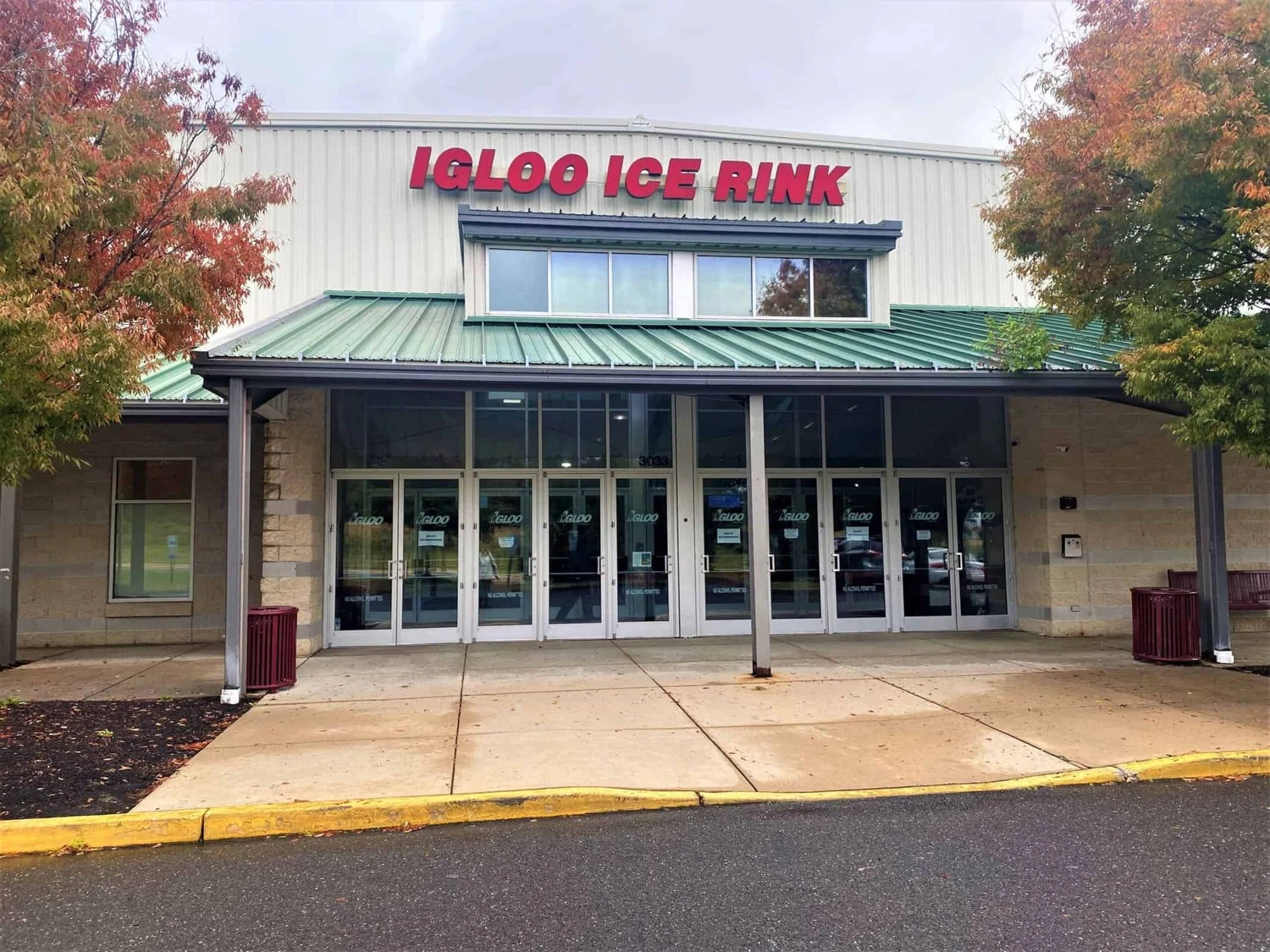 La entrada de The Igloo Ice Rink con letras rojas, árboles otoñales y un pasillo techado. — Igloo Ice Rink