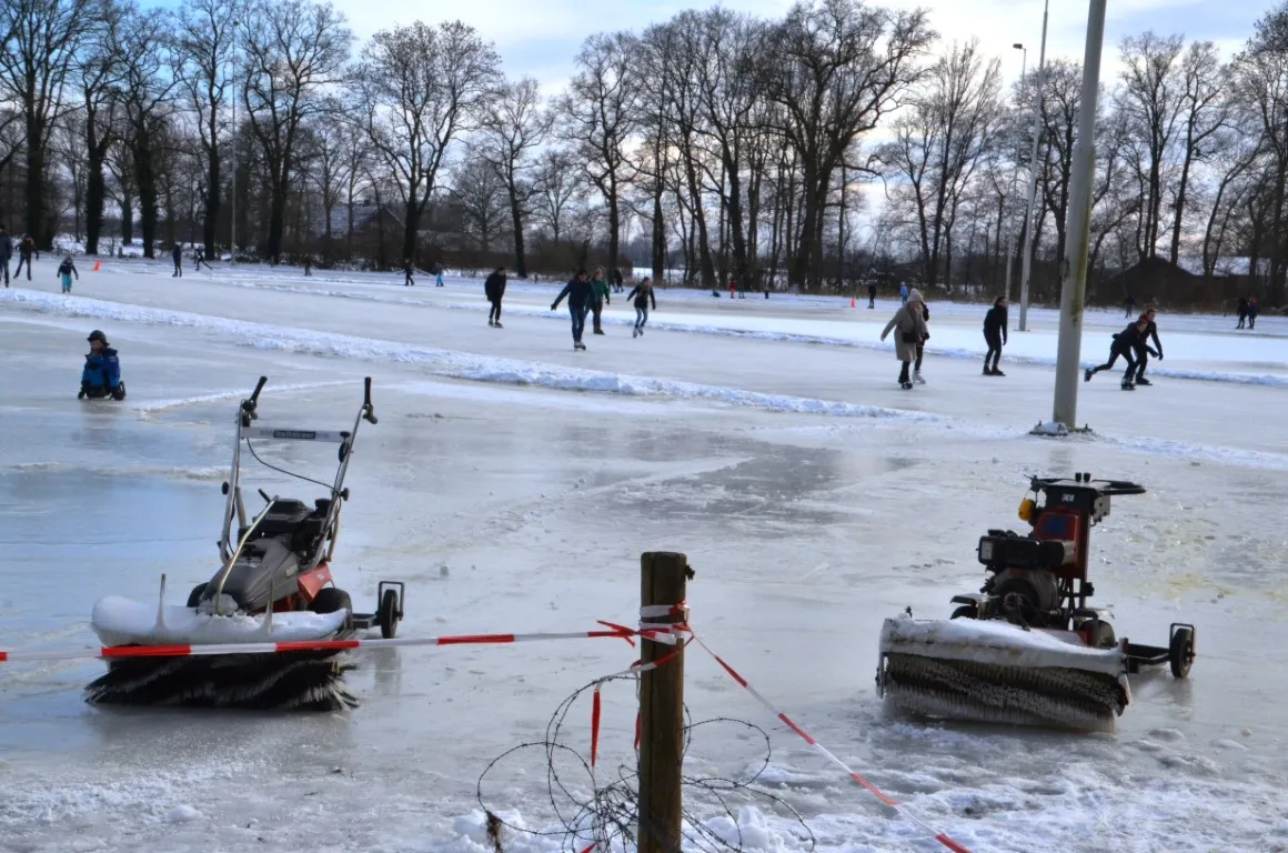 Skaters in the distance on the open ice at Hengevelde while ice sweepers stand ready on the rink. — IJsbaan Hengevelde