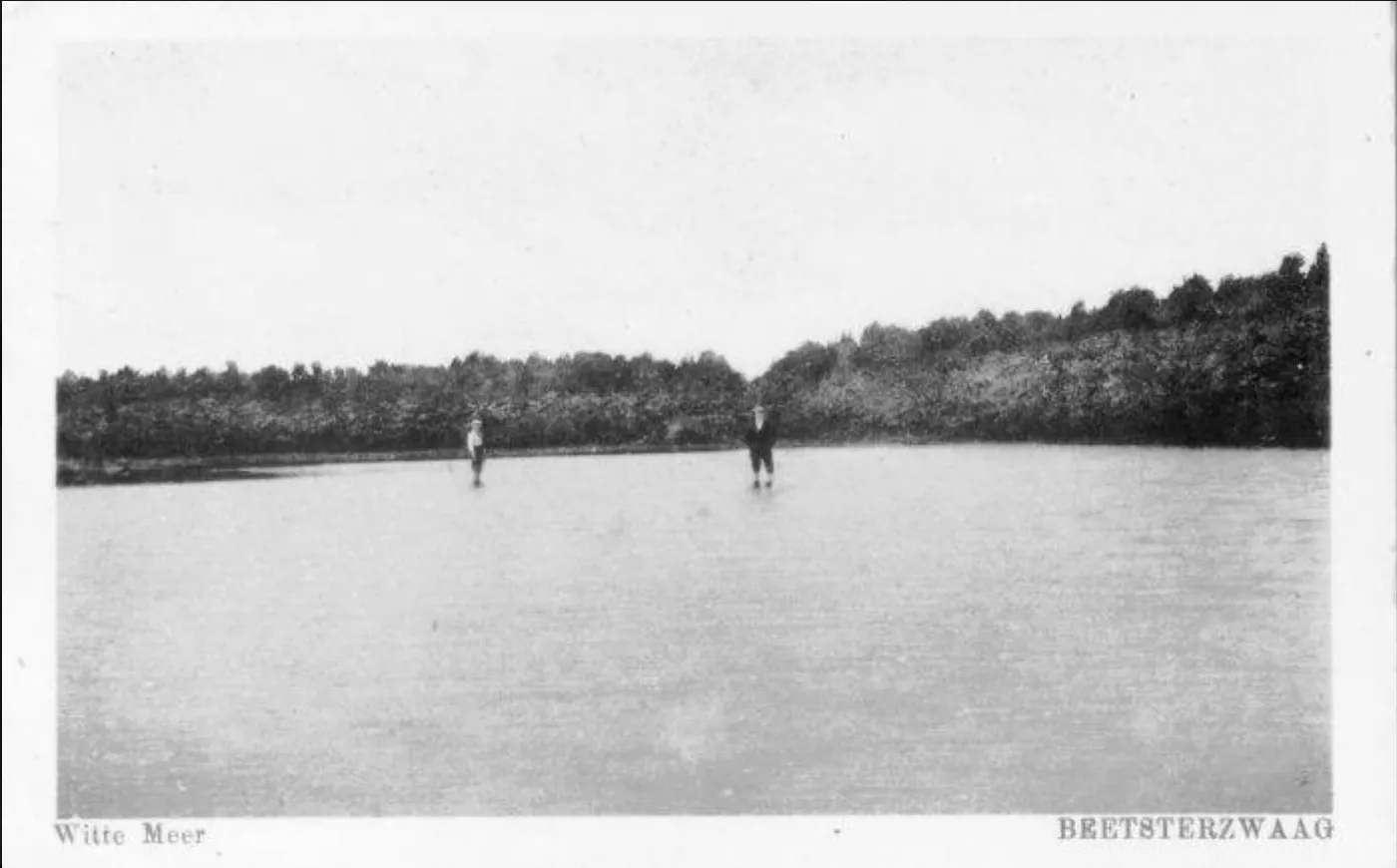 Historic postcard of two skaters on the Witte Meer (Wite Mar) forest lake in Beetsterzwaag, with the wooded shore behind. — IJsbaan Wite Mar (Iis Nocht)