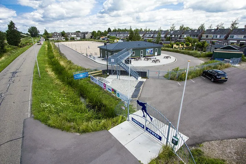 Aerial view of the Otweg combi track at Paddegat, with the oval track, the club's clubhouse with its terrace, the entrance gate and the car park beside the road. — Combibaan IJsclub Otweg (Boskoop)