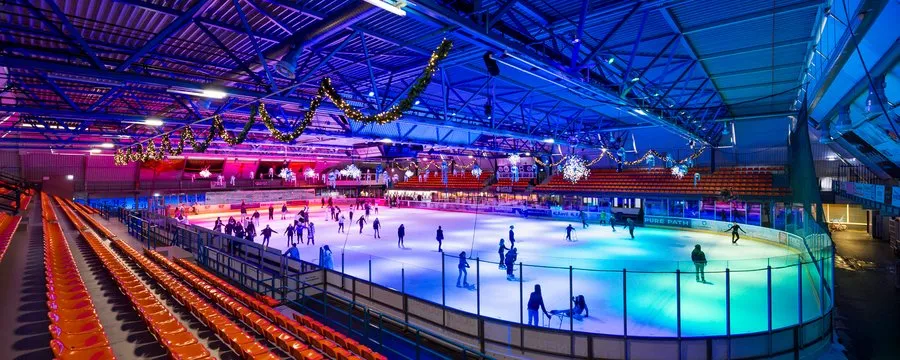 De ijshockeyhal van IJssportcentrum Eindhoven, verlicht voor een schaatsmoment in de avond – IJssportcentrum Eindhoven