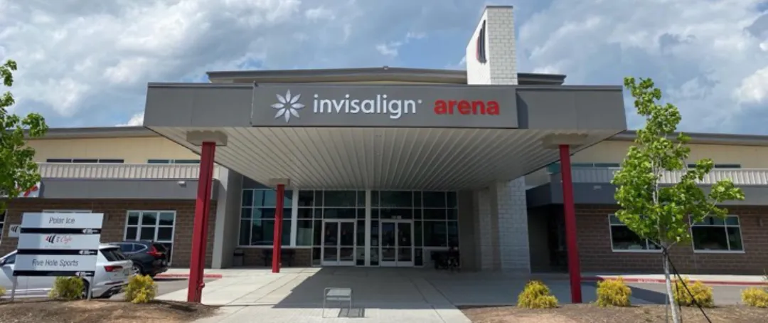 Entrance canopy and glass doors below a cloudy sky — Invisalign Arena at Wake Competition Center