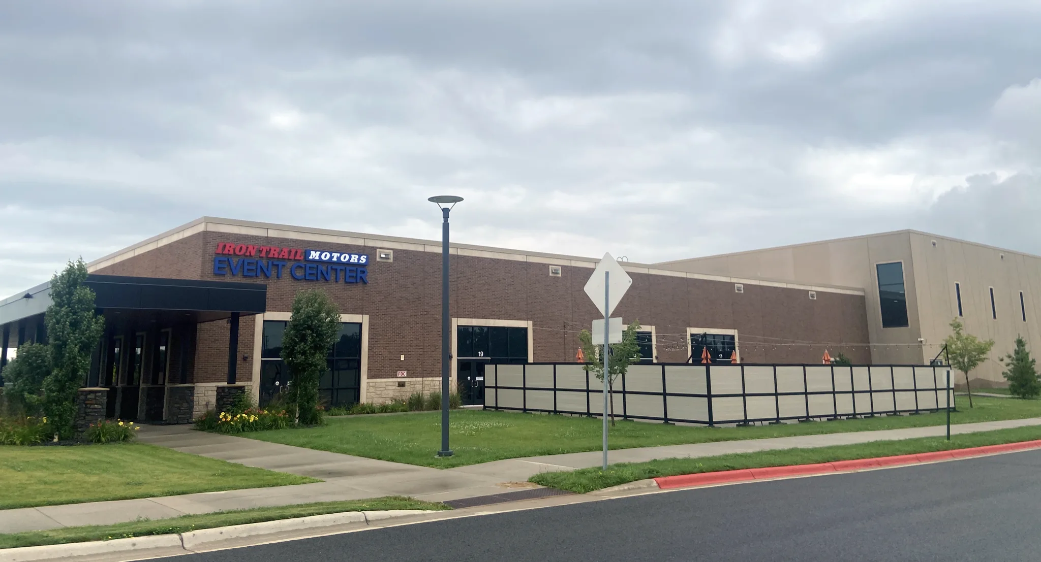 Long brown-brick front of the Iron Trail Motors Event Center on an overcast day — Iron Trail Motors Event Center