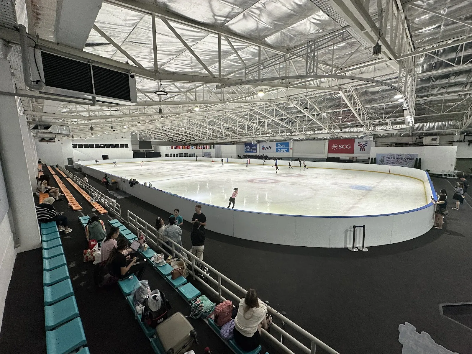 The IWIS hall seen from the spectator stand, with the full-size sheet, the boards and a few skaters at the far end. — IWIS International Ice Skating Rink