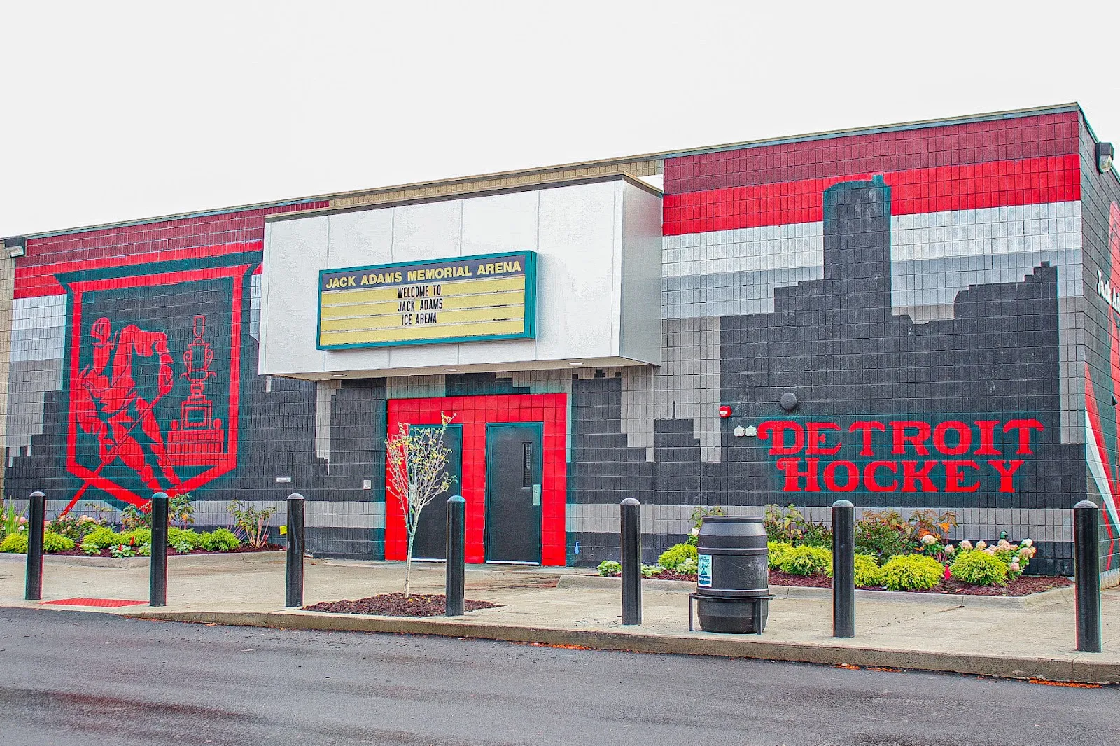 The arena's front: a marquee reading Jack Adams Memorial Arena over a red door, with a red and grey mural of a hockey player and "Detroit Hockey" on the block wall. — Jack Adams Ice Arena