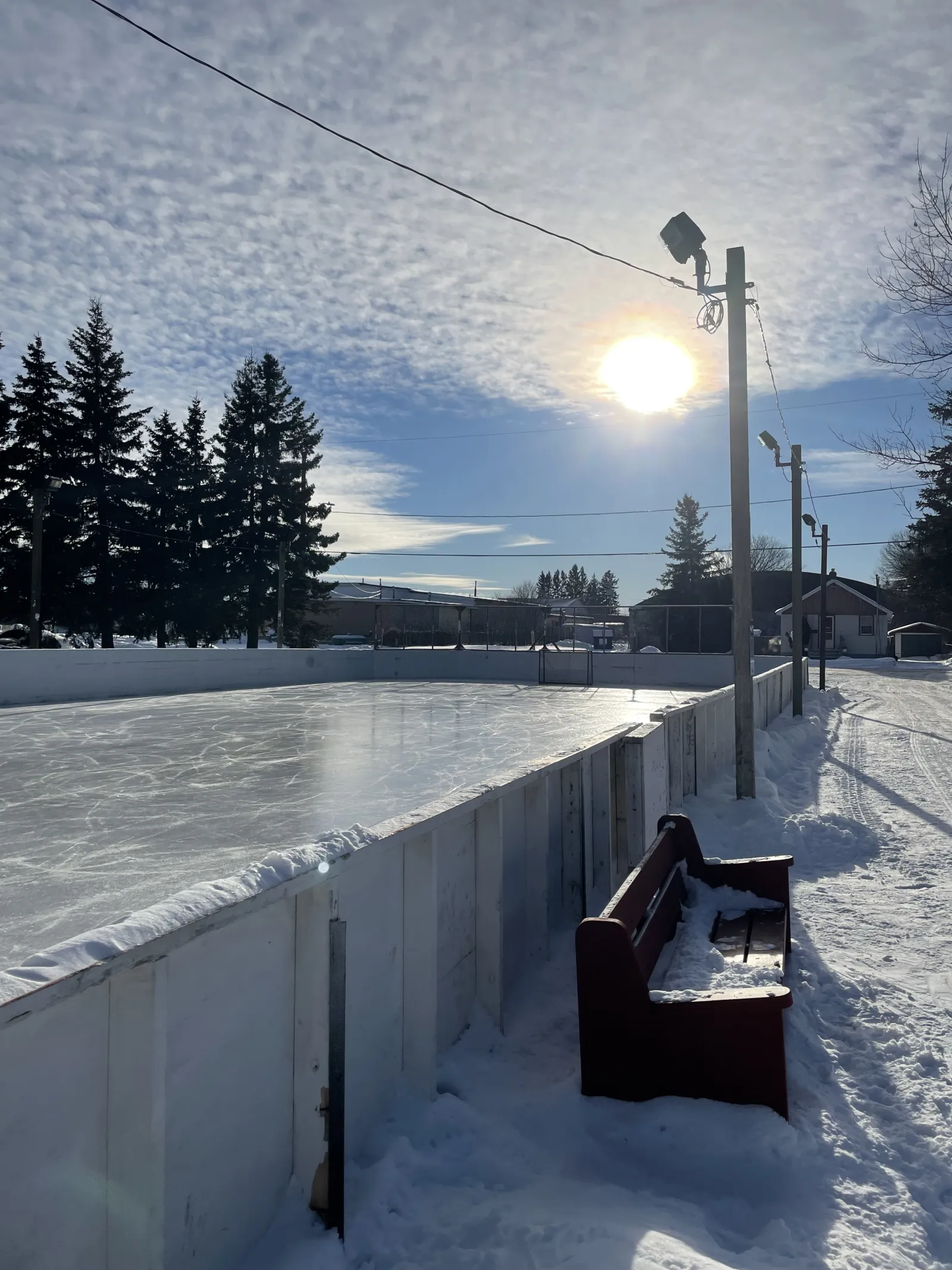 Una banca junto a las vallas en John Kusznier Memorial Park — John Kusznier Memorial Park Outdoor Rink
