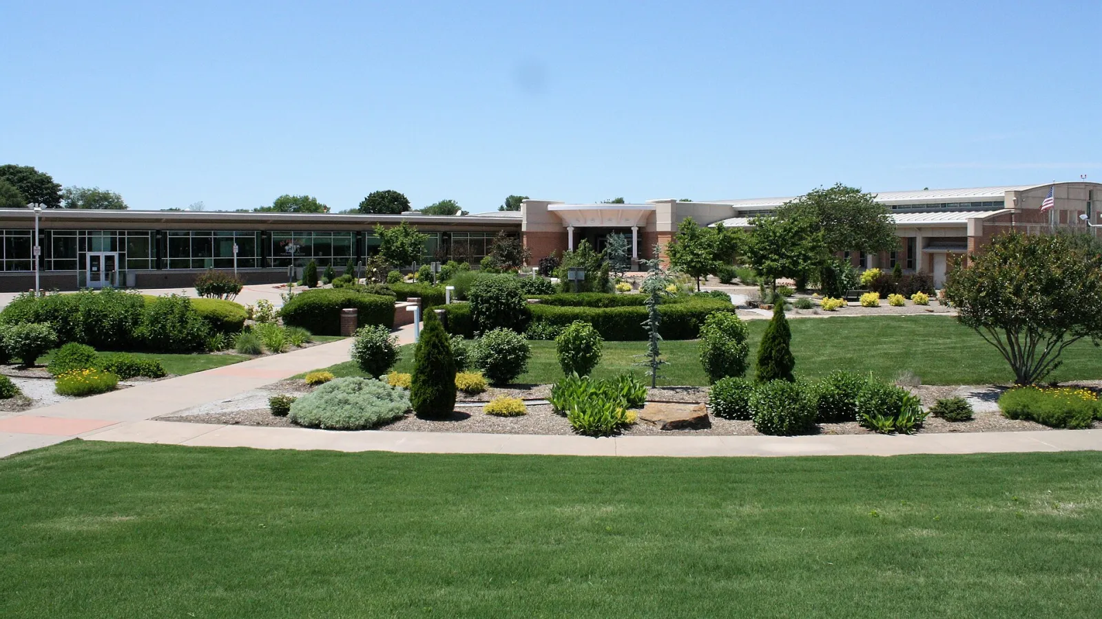 El bajo edificio de ladrillo y vidrio del Jones Center, visto a través de su jardín paisajístico. — Jones Center Ice Arena
