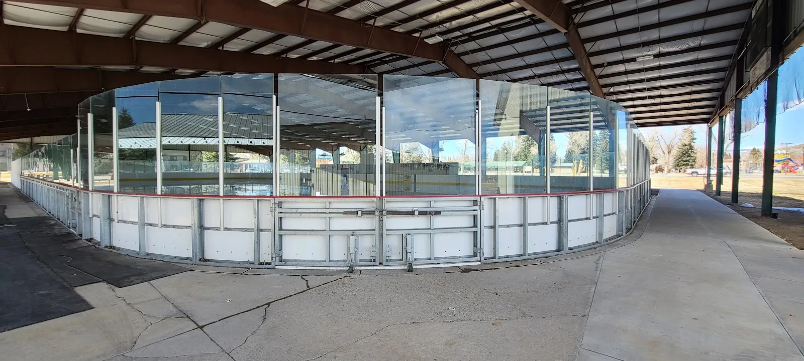 La pista cubierta al aire libre de Jorgensen Park, con vidrio sobre las vallas bajo el techo del pabellón. — Jorgensen Ice Rink & Event Center