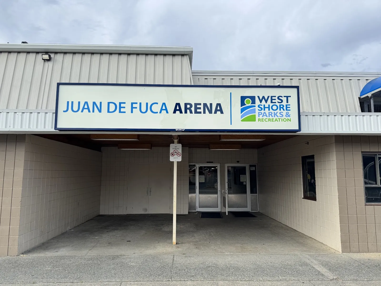 The entrance of Juan de Fuca Arena in Colwood, under the arena sign with the West Shore Parks and Recreation logo — Juan de Fuca Arena