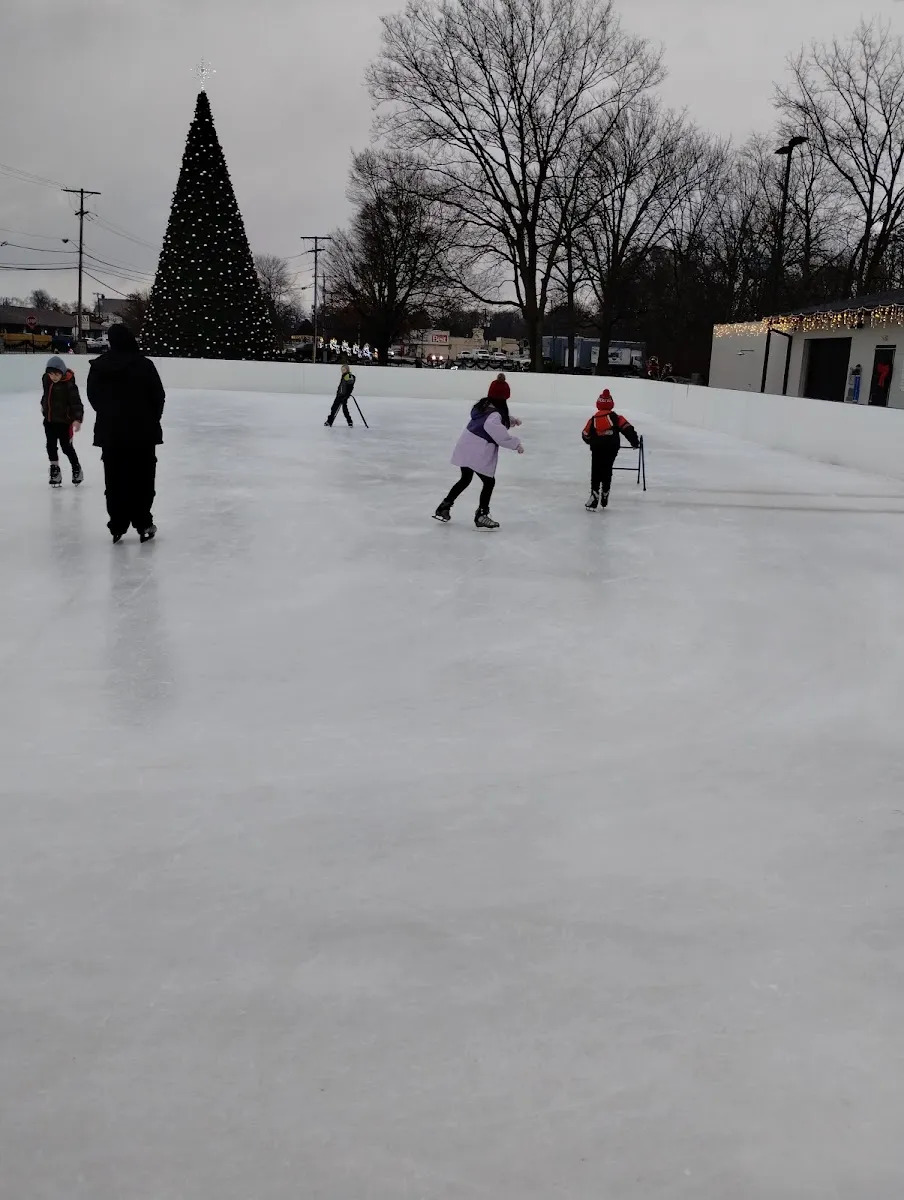 Skaters on the wide rink at Junction Park in winter light with the lit Christmas tree behind — Junction Park Ice Rink