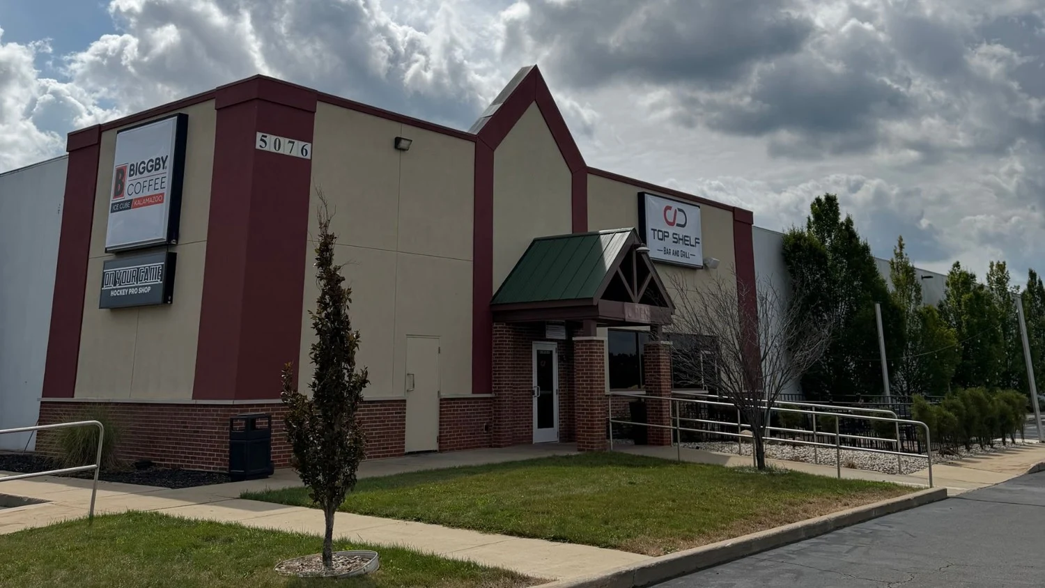 The Kalamazoo rink's angular entrance frontage and building across the lawn. — BIGGBY COFFEE Ice Cube - Kalamazoo