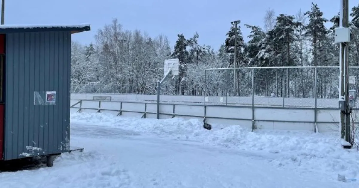 Kalannin luistelukenttä talvella: kaukalo, jonka laidan takana on koripallokori, vasemmalla harmaa kopi ja taustalla lumisia puita. – Kalannin luistelukenttä