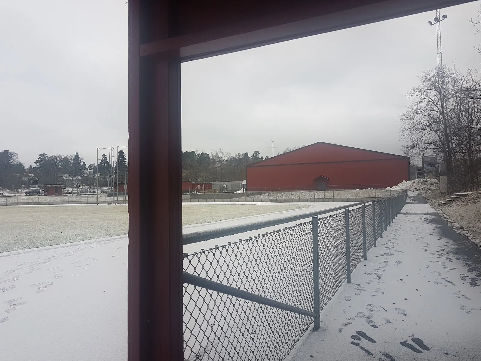 The red hall of Kallhälls ishall seen across the sports ground — Kallhälls ishall