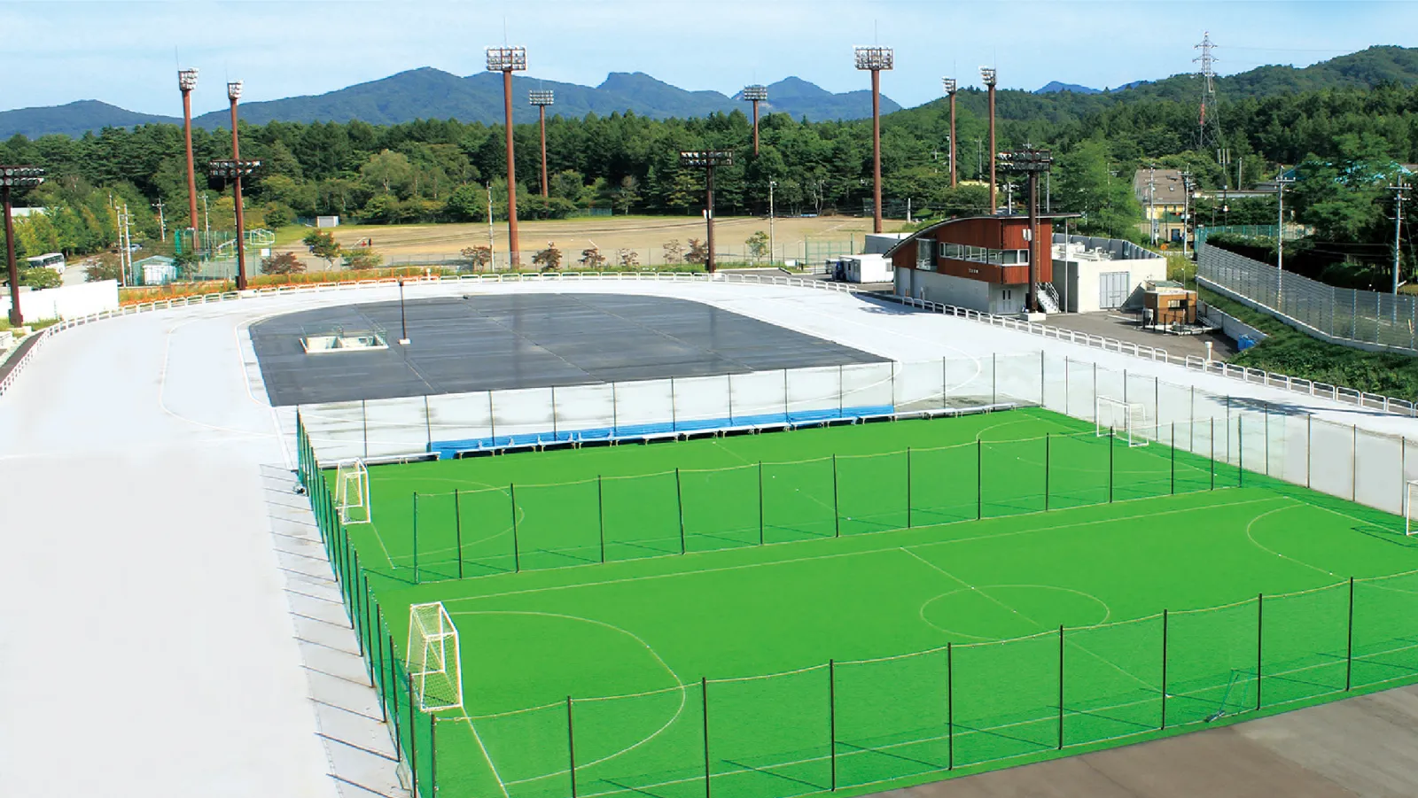 The 400 metre oval of the Kazakoshi Park outdoor rink seen from above in the warm season, with the two futsal courts laid inside the track — Karuizawa Kazakoshi Park Outdoor Skating Rink