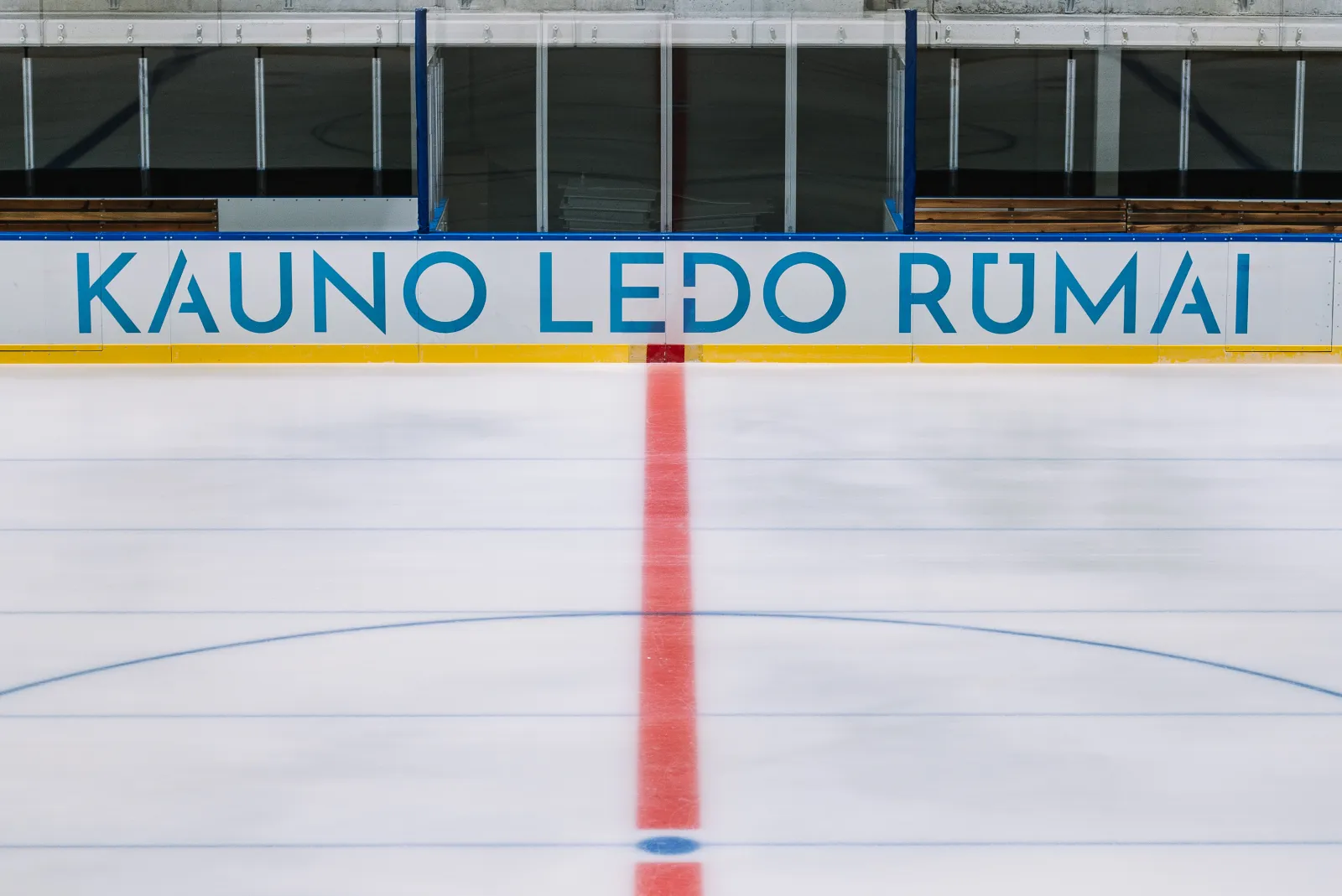 The ice at Kauno ledo rūmai with the rink boards bearing the hall's name — Kauno ledo rūmai
