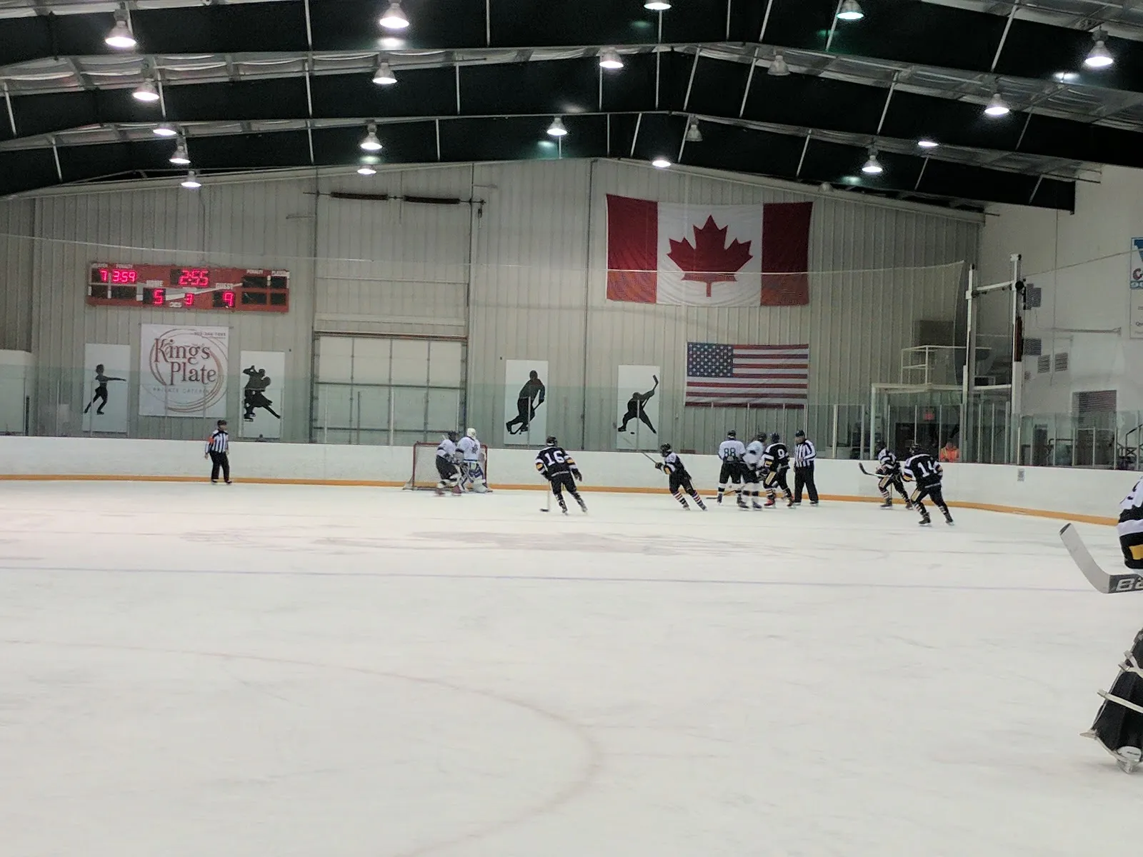A game under way on the ice at the Keeler Centre Arena, with the scoreboard and flags on the far wall — Keeler Centre Arena