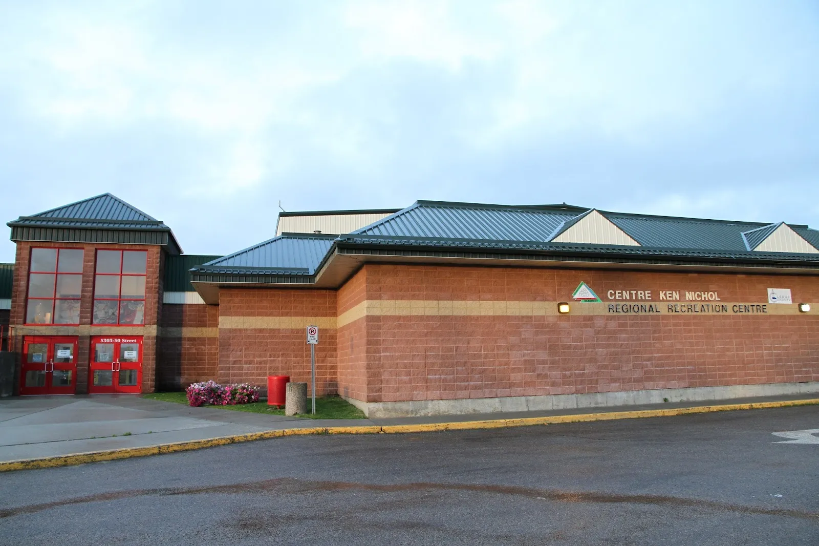 The red-brick front of the Centre Ken Nichol Regional Recreation Centre, with its bilingual sign and green metal roofs. — Ken Nichol Regional Recreation Centre